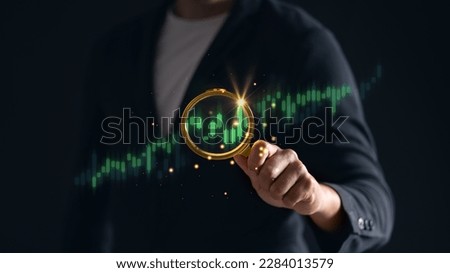 A close-up of a man using a magnifying glass to examine a green stock graph on a digital device. analysis and trading concept.