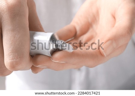 Woman squeezing out ointment from tube on her finger, closeup Royalty-Free Stock Photo #2284017421