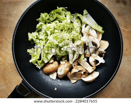 A round skillet with sliced mushrooms and Chinese cabbage, ready to be fried as a side dish for breakfast.