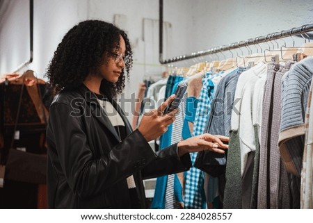 Young woman showing a new garment to her friend over video call. She is in a shop. Royalty-Free Stock Photo #2284028557