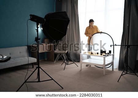 Photographer preparing for shooting by setting up equipment in home photo studio. Copy space Royalty-Free Stock Photo #2284030311