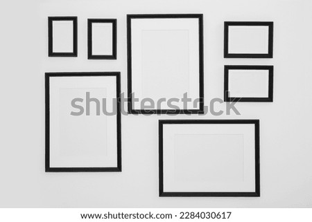 Different empty frames hanging on white wall