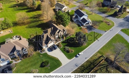 Subdivision street with two-story houses, front garage, well-trimmed grassy yards, no fenced backyard in low density housing neighborhood suburbs Rochester, New York, USA. Aerial view suburban homes