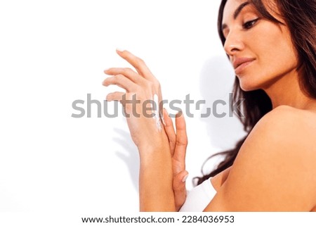 Extreme close up of young caucasian woman hands with white manicure and cream on them. Beautiful female fingers are smeared with white cream. White isolated background. Free space for text.