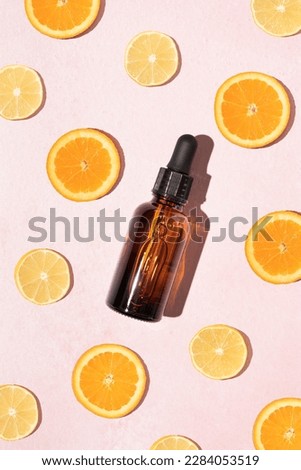 Vivid fresh vitamin C serum concept with brown glass cosmetic dropper bottle and slices of lemon and orange on a pastel pink background. Natural bright skincare design. Royalty-Free Stock Photo #2284053519