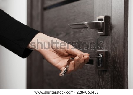 Woman unlocking door with key, closeup view Royalty-Free Stock Photo #2284060439