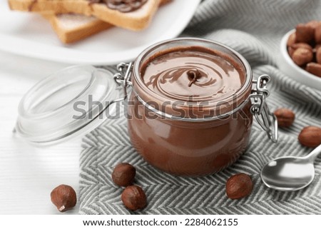 Jar with chocolate paste and nuts on white table, closeup Royalty-Free Stock Photo #2284062155