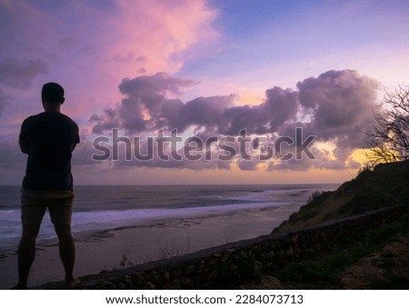 Silhouette of happy Man Standing on Beach at Sunset and looking at horizon