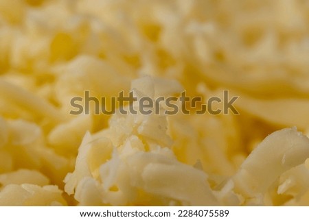 Hard cheese with holes grated into thin small slices, small pieces of cheese for pizza and snacks