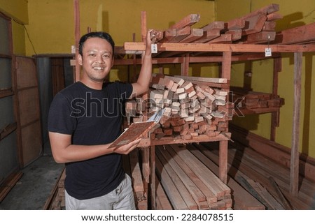 Handsome Asian Man is smiling while checking his carpentry workshop