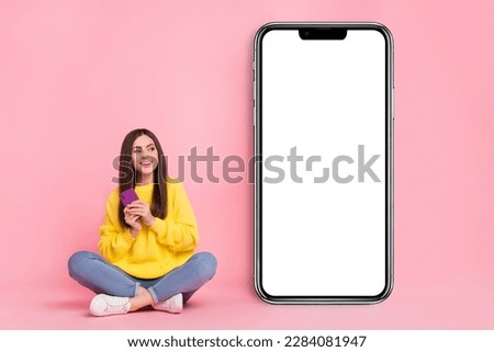 Full body photo of young cheerful girl sit floor use mobile promo look empty space share isolated over pink color background