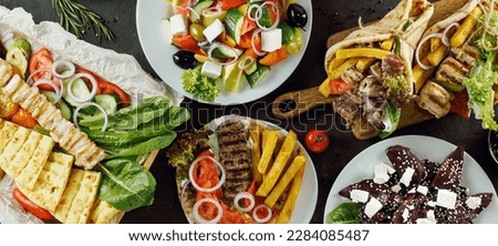 Greek food assorted on dark background, long horizontal banner. Gyros, greek salad, souvlaki - selected of greek cuisine assortment