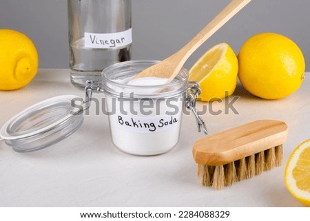 Eco friendly natural cleaners baking soda, vinegar and lemon on a gray background.The concept ecological cleaning, disinfecting, removing stains. High quality photo Royalty-Free Stock Photo #2284088329
