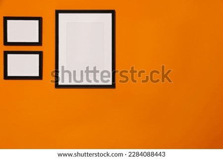Empty frames hanging on orange wall. Mockup for design