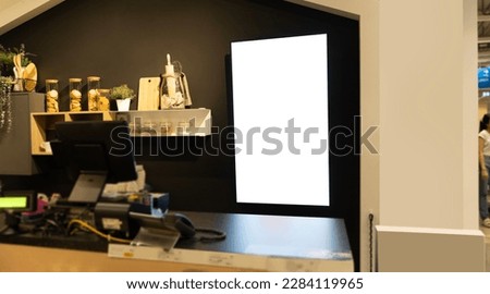 Interior of a modern coffee bar with a blank signboard behind the counter and items on the shelves. Mockup. Contemporary coffee shop interior with blank posters.