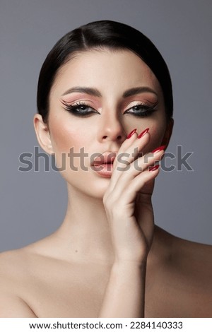 Beauty portrait of a woman, pink eye shadow makeup, arrows and long eyelashes. Brunette woman, red nail polish, natural cosmetics Royalty-Free Stock Photo #2284140333