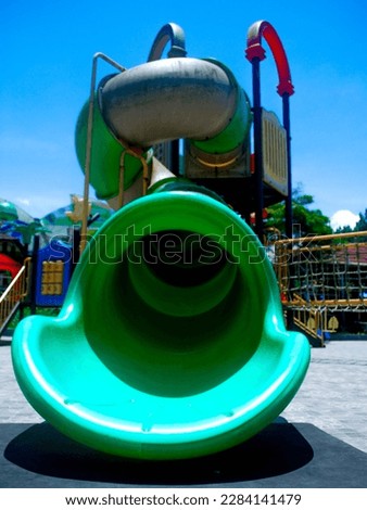 Colorful Playground with a green plastic slide in the playground area. with a spiral shape and ceramic floor.