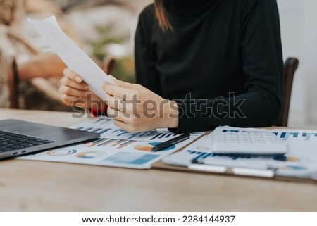Working of businesswoman or accountant working on laptop computer analyzing business report graphs and financial charts in workplace concept of finance and investment.