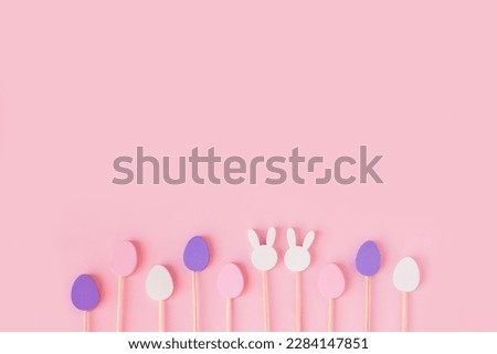 Easter frame composition with minimal style eggs and rabbit wood toys on pastel light pink background. Trendy composition, holiday concept. Flat lay, top view, place for text