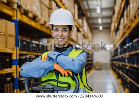 Portrait of warehouse female worker in reflective vest with a pallet truck. Royalty-Free Stock Photo #2284149603
