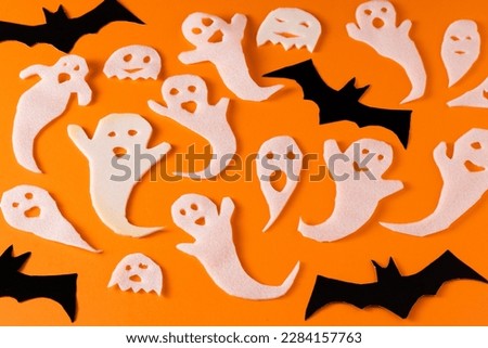 White ghosts and bat craft for Halloween party. Wrapping paper ghost on orange background top view. Cartoon creepy Whisper. DIY hand made. Set boo characters.