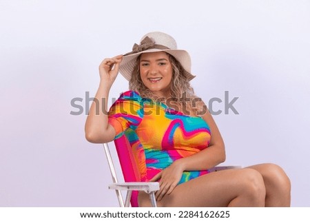 Young woman on vacation sitting on beach chair and summer outfit on background for clipping. Holiday and travel promotion