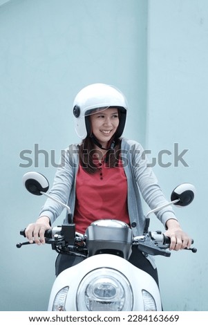 mature asian woman showing excited expression while riding motorcycle Royalty-Free Stock Photo #2284163669