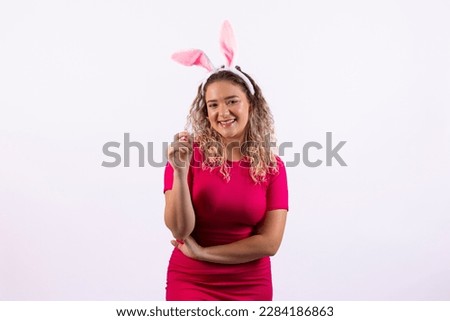 Adorable young woman in bunny ears smiling pointing free side to easter text