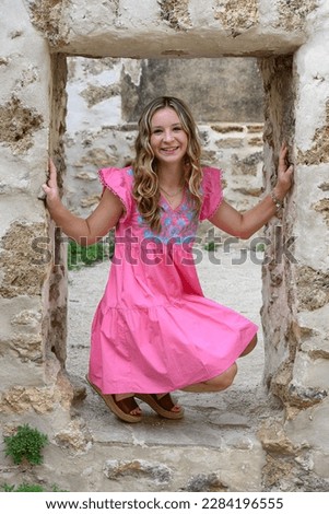 Young pretty teenage girl posing in a historic setting for her high school graduation photos