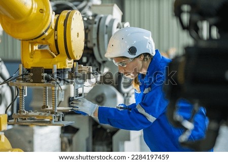 woman engineer in uniform helmet inspection check control heavy machine robot arm construction installation in industrial factory. technician worker check for repair maintenance electronic operation Royalty-Free Stock Photo #2284197459