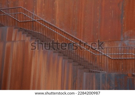 Stairs along a rusty steel wall