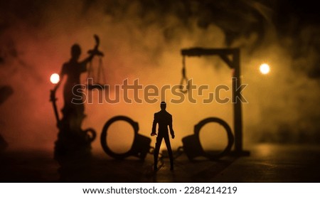 Legal law or crime and execution concept. Death penalty miniatures on table. Man alone looking to execution at night. Artwork decoration with handcuffs, Statue of Justice and mallet of justice Royalty-Free Stock Photo #2284214219