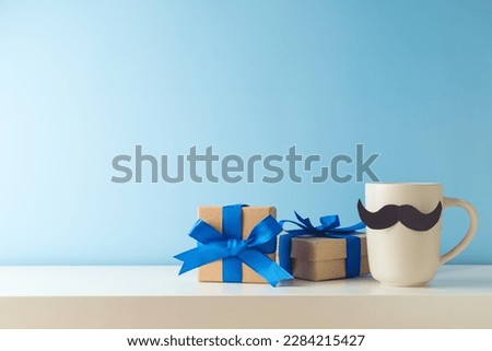 Father's day celebration with coffee cup, mustache and gift box on white table over blue background