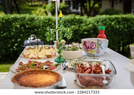 
Table set outdoors with midsummer food and midsummer pole decoration