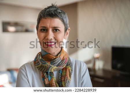 One woman senior mature female with short gray hair happy smile carefree at home in apartment room stand alone in morning wear white shirt real person copy space Royalty-Free Stock Photo #2284228939
