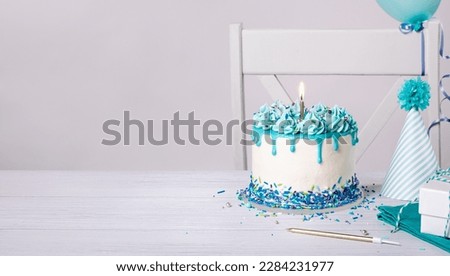 Blue Birthday cake, hats and balloons over white background.