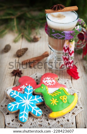 Homemade gingerbreads in the form of a snowflake and a green horse on a wooden table and a glass of warm cacao with a small knit scarf. Selective Focus on gingerbreads. Toned