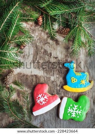 Homemade christmas gingerbreads painted as a blue horse, a red hat and green boot on the wooden background with fir branches. Selective focus and place for text. Toned