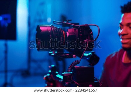 Young African American cameraman working with professional camera and shooting process in studio Royalty-Free Stock Photo #2284241557