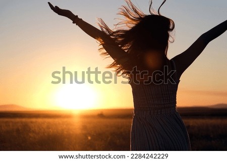 silhouette of a girl with her hair blowing in the wind at sunset Royalty-Free Stock Photo #2284242229