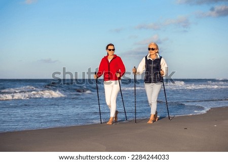 Nordic walking - two women training on beach  Royalty-Free Stock Photo #2284244033