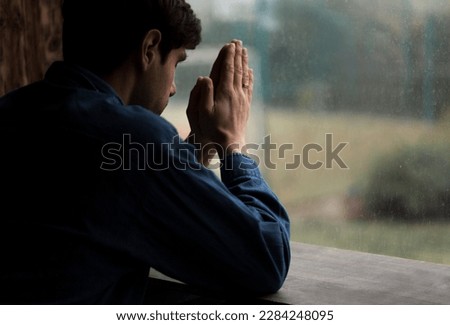Young mam praying from window. religion concept.