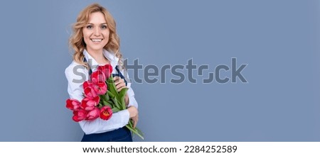 glad girl in apron with spring tulip flowers on grey background. Woman isolated face portrait, banner with mock up copy space.