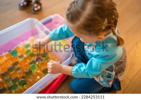 Little girl playing with sensory water beads, hydrogel balls. Sensory development and experiences, themed activities with children, fine motor skills development. High quality photo Royalty-Free Stock Photo #2284253111