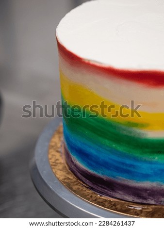 pastry chef working on a frosted cup cake with lgbt rainbow colours for wedding union party celebration. Birthday cupcake. Rainbow paper cup liners. Happy Birthday. Celebration Holidays. LGBT pride.