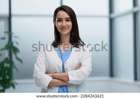 female doctor in lab coat with arms crossed against