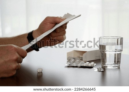 Person reading patient instruction leaflet at the tablets and glass of water Royalty-Free Stock Photo #2284266645