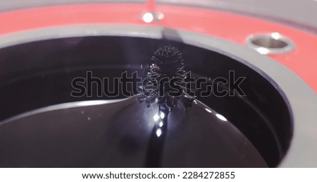 Experiment on the movement of a ferromagnetic black liquid under the action of a magnetic field. Ferrofluid takes on bizarre sharp shapes under the influence of a magnetic field. Royalty-Free Stock Photo #2284272855