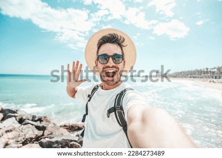 Handsome young man taking selfie at beach summer vacation - Smiling guy having fun walking outside - Summertime holidays and technology concept