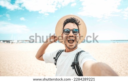 Handsome young man taking selfie picture at beach summer vacation - Smiling guy having fun walking outside - Summertime holidays and technology concept